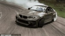 a bmw m2 drifting on a dirt road with smoke coming out of the windshield .