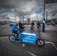 a man riding a bike with a box that says any task etn donate