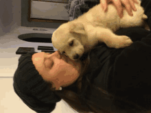 a woman wearing a black hat is kissing a puppy on the nose