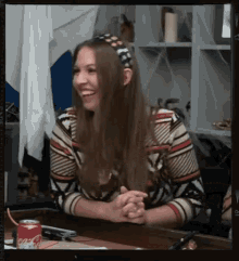 a woman is smiling while sitting at a table with a can of coca cola in front of her .