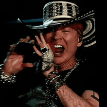 a man wearing a cowboy hat is singing into a microphone while making a funny face .