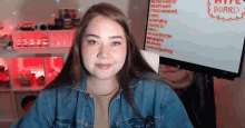 a girl in a denim jacket is smiling in front of a white board that has the word board on it