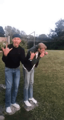 two men are standing next to each other in a grassy field .