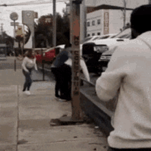 a man taking a picture of a group of people on a sidewalk with a sign that says no parking