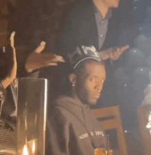 a man wearing a hat is sitting at a table in a dark room with candles .