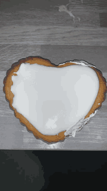 a heart shaped cookie with white frosting on top of it