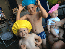 a boy wearing a yellow hat stands next to another boy wearing a pink hat