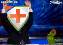 a man in a suit holds up a shield with an orange cross on it in front of a kermit the frog