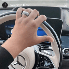 a person wearing a ring driving a mercedes