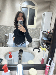 a woman is taking a selfie in a bathroom with a phone that says ' selfie ' on it