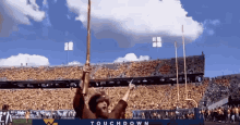 a man in a cowboy hat holds up a flag in front of a stadium that says touchdown on the bottom