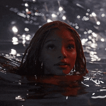 a girl with red hair is swimming in the water at night