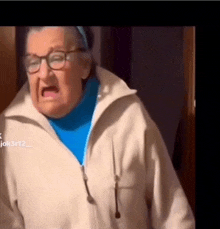 an elderly woman wearing glasses and a blue turtleneck is screaming .