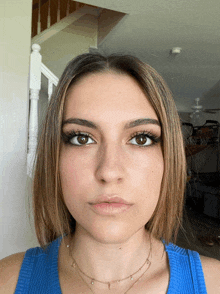 a young woman wearing a blue tank top and a gold necklace