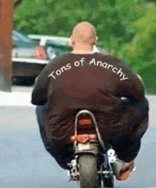 a man is riding a motorcycle with a shirt that says tons of anarchy on it .