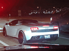 a white lamborghini is parked in a parking lot at night