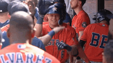 a group of baseball players are standing in a dugout and one of them is wearing a jersey that says be on it