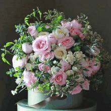 a bouquet of pink roses and white flowers in a box with a ribbon .