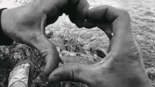 a black and white photo of a person making a heart with their hands