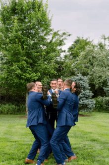 the groom and his groomsmen are hugging the groom in a field