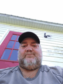 a man with a beard is standing in front of a house