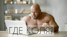 a shirtless man is eating a hamburger and looking at a laptop