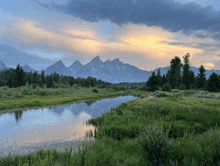 a river with mountains in the background and trees on the side