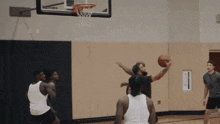 a group of men are playing basketball in a gym and one of them is jumping to catch the ball