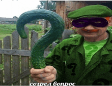 a man dressed as the riddler is holding a large cucumber