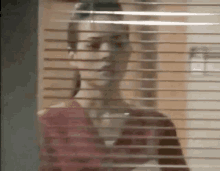 a blurry picture of a woman behind a window with blinds .