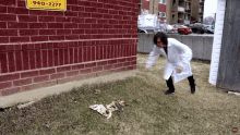 a man in a lab coat is standing in front of a brick wall with a sign that says 940-2277