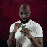 a man with a beard and a white shirt is standing in front of a red background with his fists in the air .