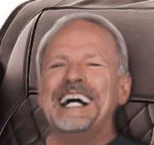 a man with a beard is laughing while sitting in a car seat .