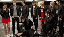 a group of people are standing around a man laying on the ground .