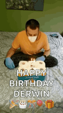 a man wearing a face mask and gloves is sitting on a bed with a birthday cake made out of toilet paper