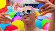 a man with pink hair is surrounded by colorful balloons