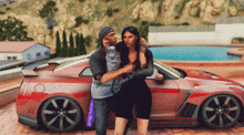 a man and a woman pose in front of a red car