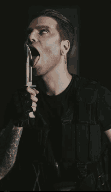 a man with a tattoo on his ear is sticking his tongue out and holding a knife in his mouth