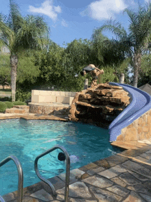 a swimming pool with a slide and a waterfall surrounded by palm trees