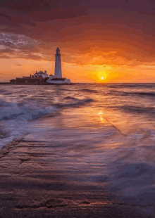 a lighthouse sits on the shore of the ocean at sunset