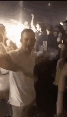 a man in a white shirt is dancing in front of a crowd