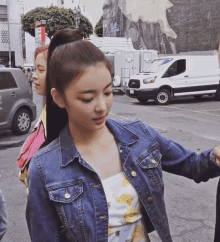 a woman in a denim jacket is standing in front of a white van