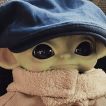 a baby alien wearing a blue hat and scarf .