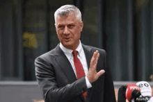 a man in a suit and tie is standing in front of a microphone and giving a thumbs up .