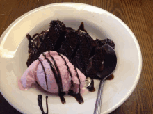 a white plate with a piece of chocolate cake and a scoop of strawberry ice cream