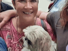 a woman is holding a small white dog in her arms .