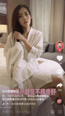 a woman in a white robe is sitting on a bed with chinese writing on the screen