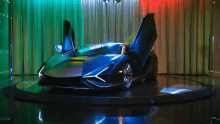 a black sports car with its doors open is on display in a showroom