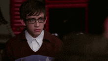 a young man wearing glasses and a sweater has a serious look on his face