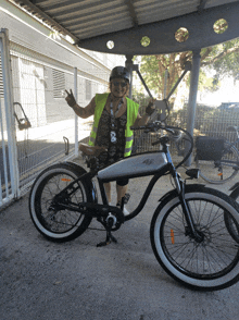 a woman wearing a yellow vest and a helmet stands next to a bicycle